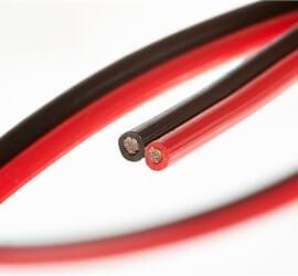 view of a dual ribbon cable in red and black tubing on a white background.