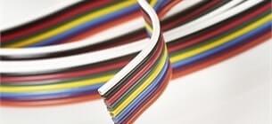 close up view of rainbow coloured ribbon cable wrapped in a circle on a white background